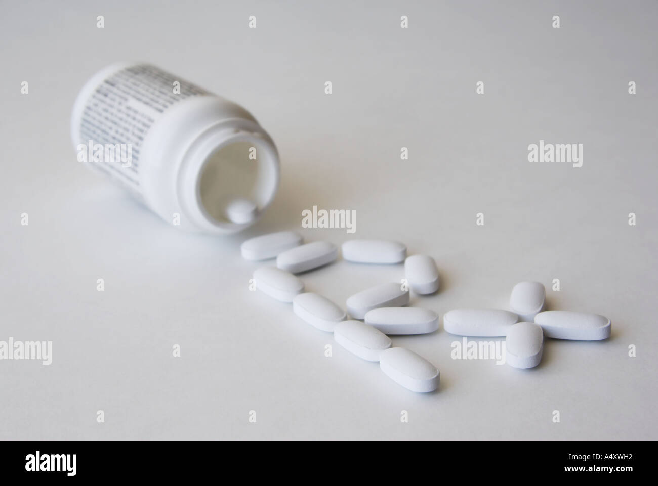 La droga versato all'esterno di una pillola bottiglia formando un segno prescrizione, iscritto sulla bottiglia illeggibile Foto Stock