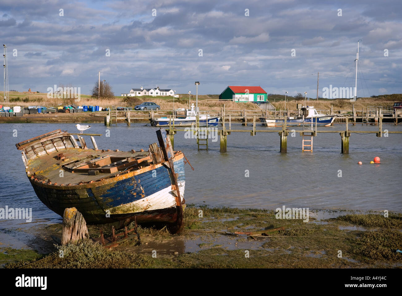 Una vecchia barca da pesca che giace nel fango con la bassa marea nel porto di segale Foto Stock