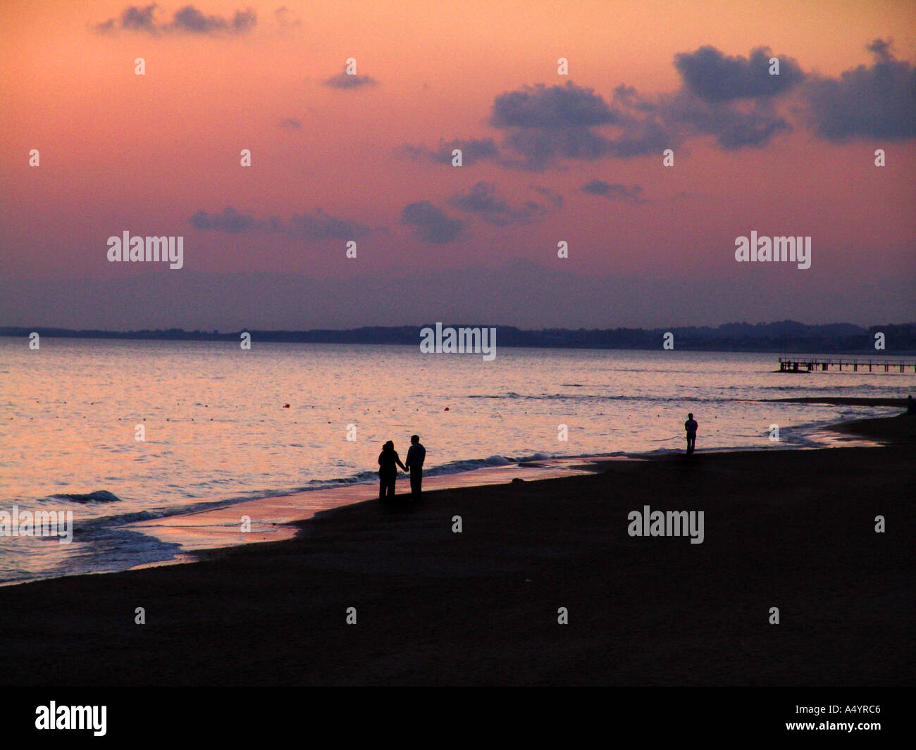 Giovane passeggiate in spiaggia al tramonto Paar spaziert am Strand in den Sonnenuntergang hinein Foto Stock