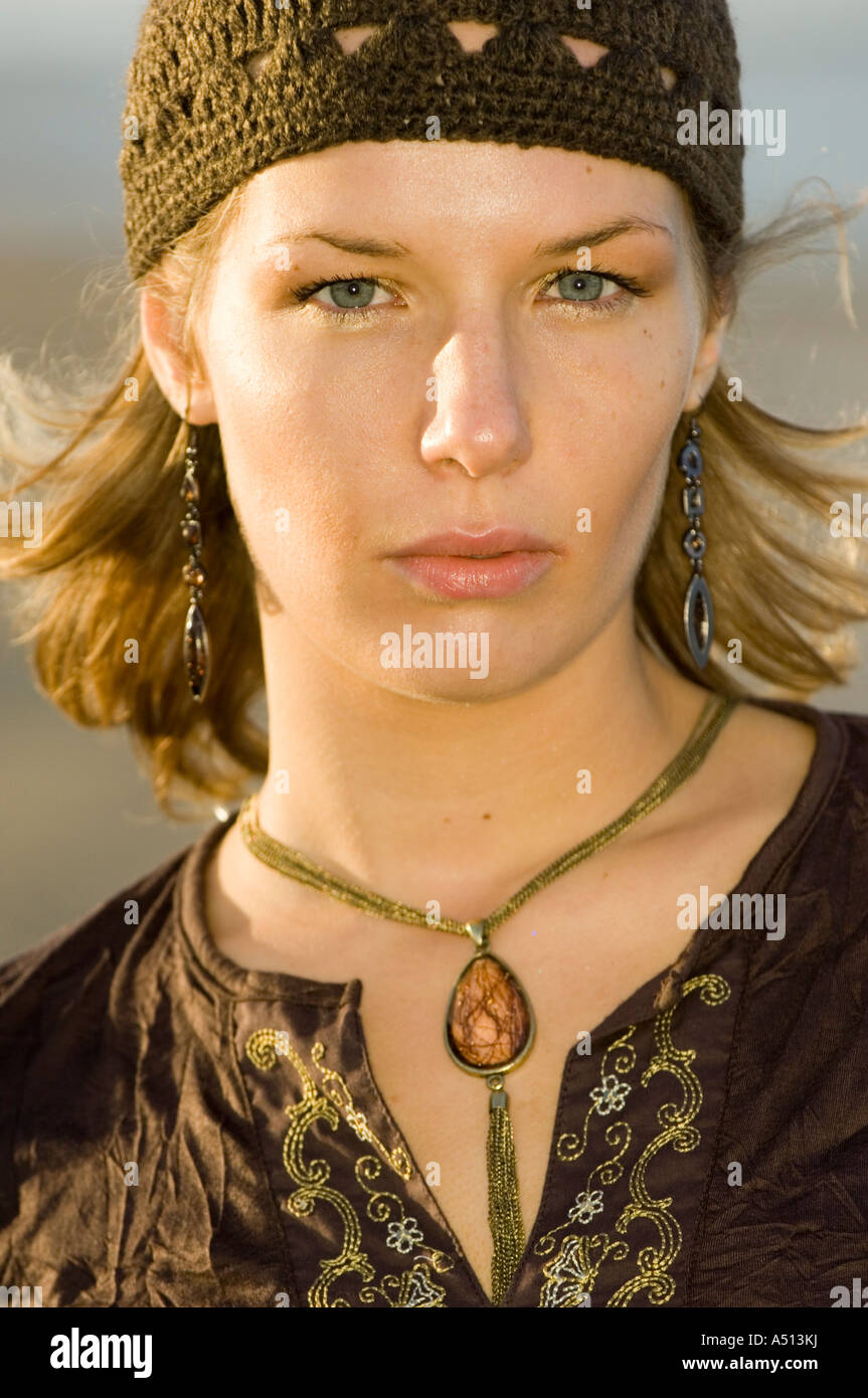 Ritratto di giovane e bella donna che guarda dritto verso la fotocamera e vestito in abiti di colore marrone. Foto Stock