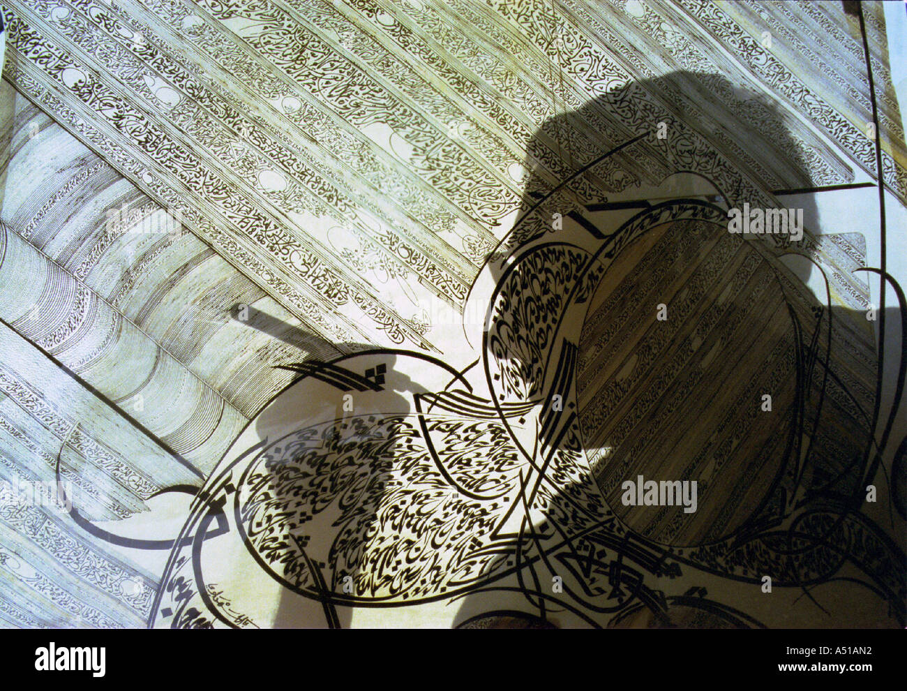 L'ombra di un calligrafo scende attraverso una squisita il testo arabo in un museo display Foto Stock