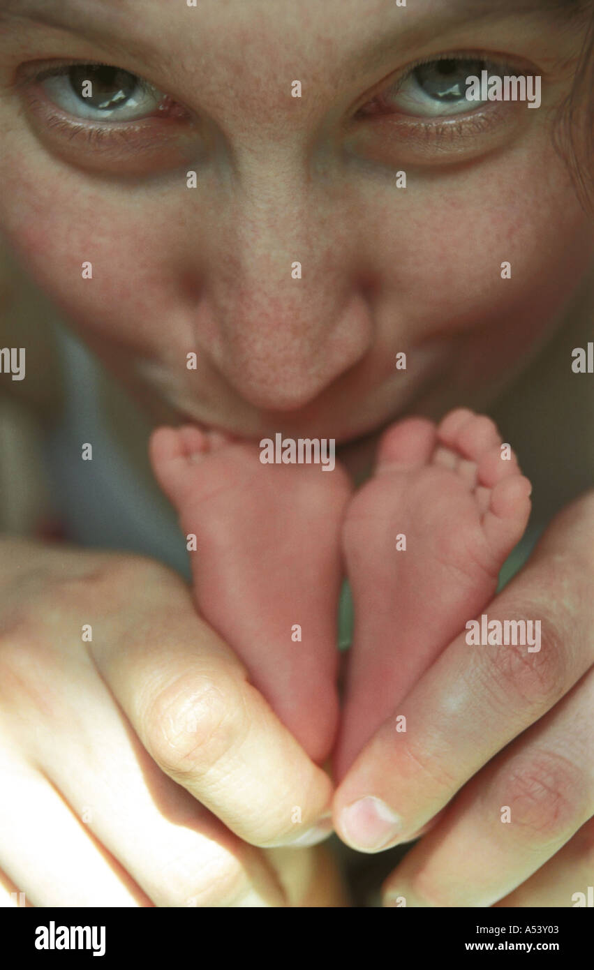 Madre teneramente trattiene e baci piccoli piedini del suo 6 giorni baby Russia Foto Stock