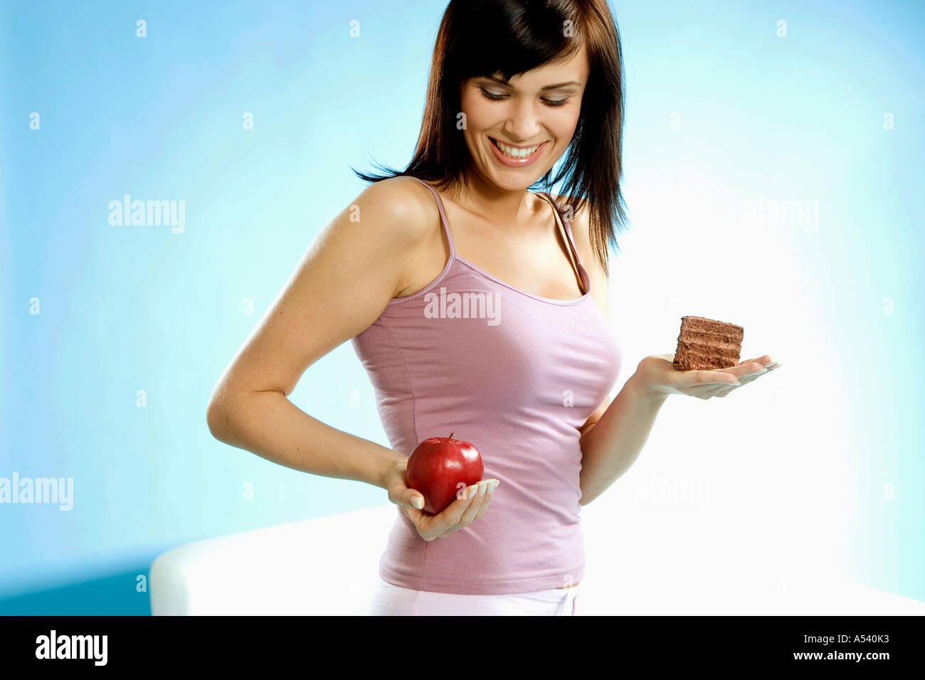 Giovane donna holding pezzo di torta e Apple in mano Foto Stock