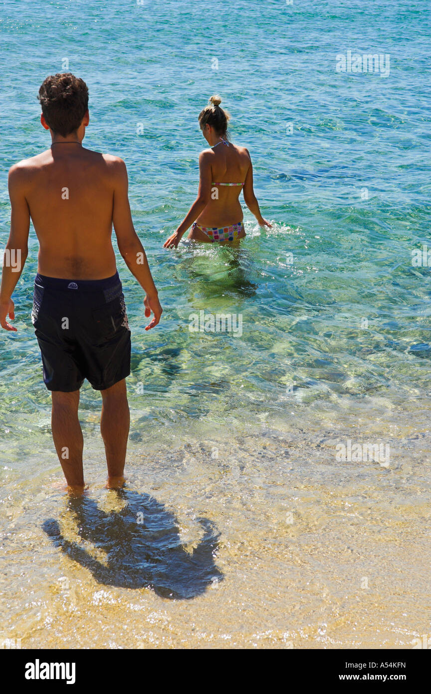 Coppia in vacanza entra in acqua in chiaro blu azzurro mare in spiaggia Foto Stock