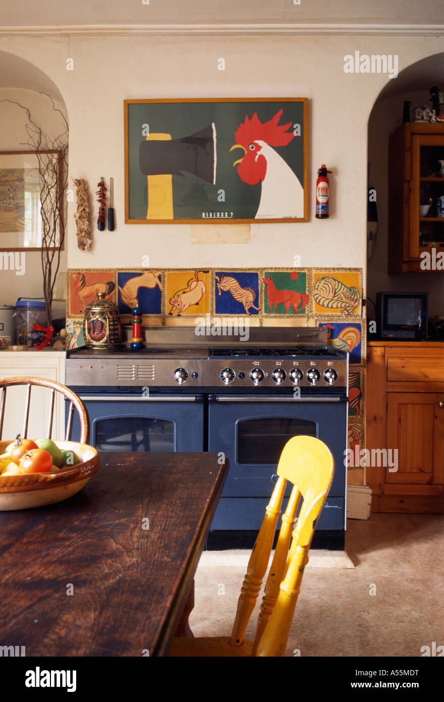 Cucina con foto e piastrelle colorate sopra il forno blu e tavoli e sedie  in legno Foto stock - Alamy