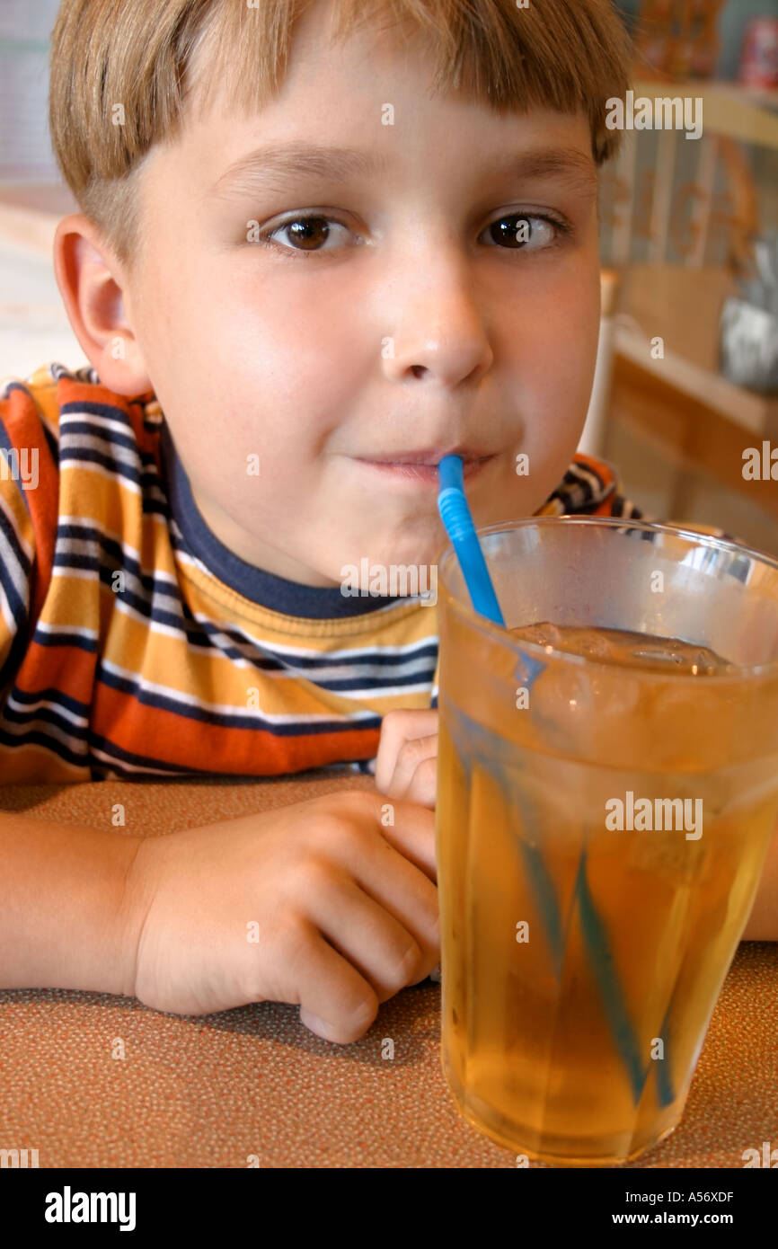 Ragazzo giovane sorseggiando un succo di mela in Cafe Foto Stock
