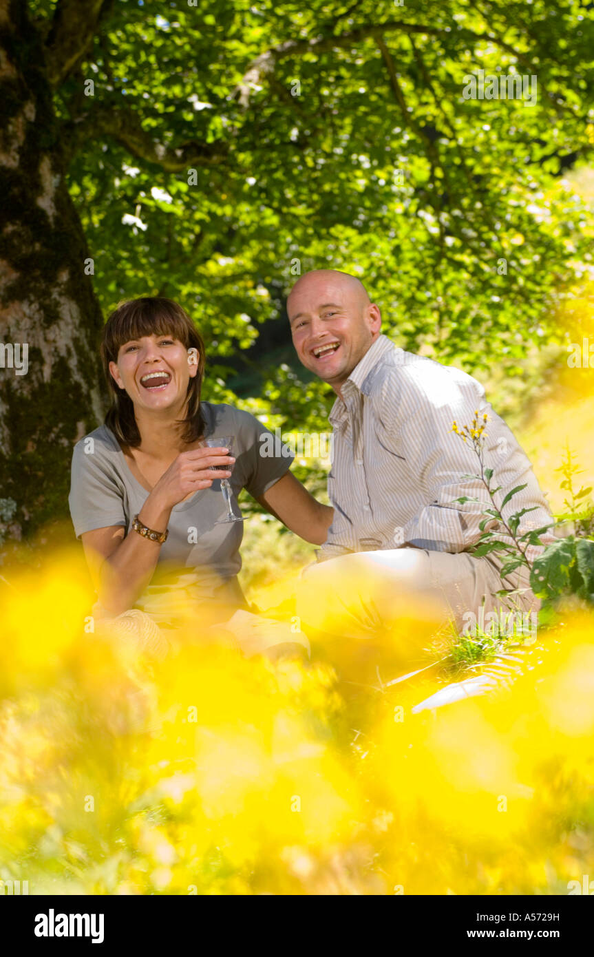 Giovane avente picnic sotto agli alberi, sorridente Foto Stock