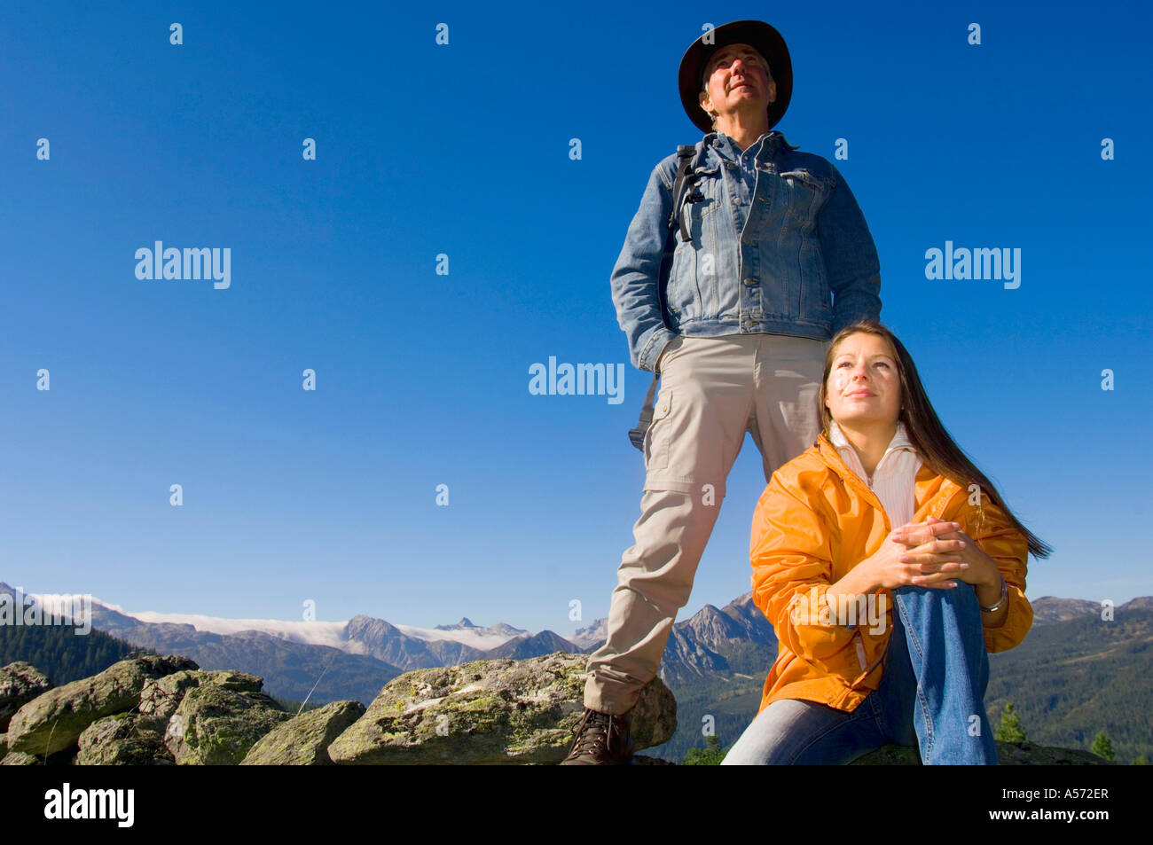 Matura in montagna, uomo, donna seduta sulle rocce Foto Stock