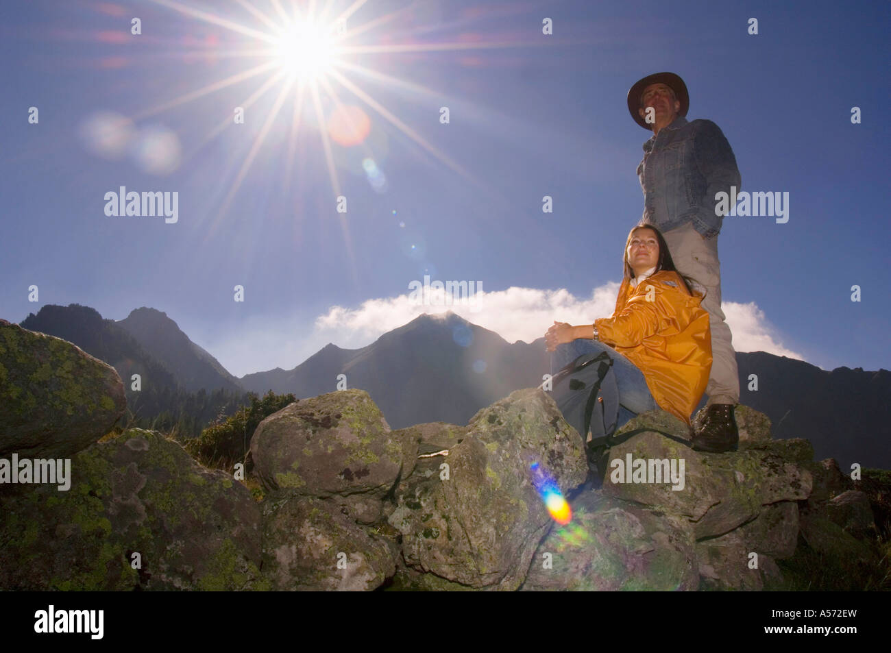Matura in montagna, uomo, donna seduta sulle rocce Foto Stock