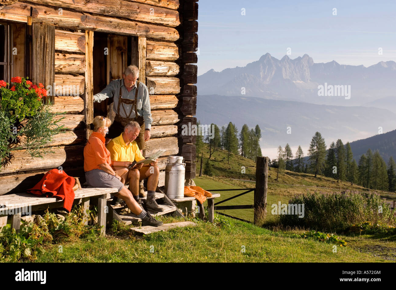 Coppia matura seduti davanti al rifugio alpino, parlando di agricoltore Foto Stock
