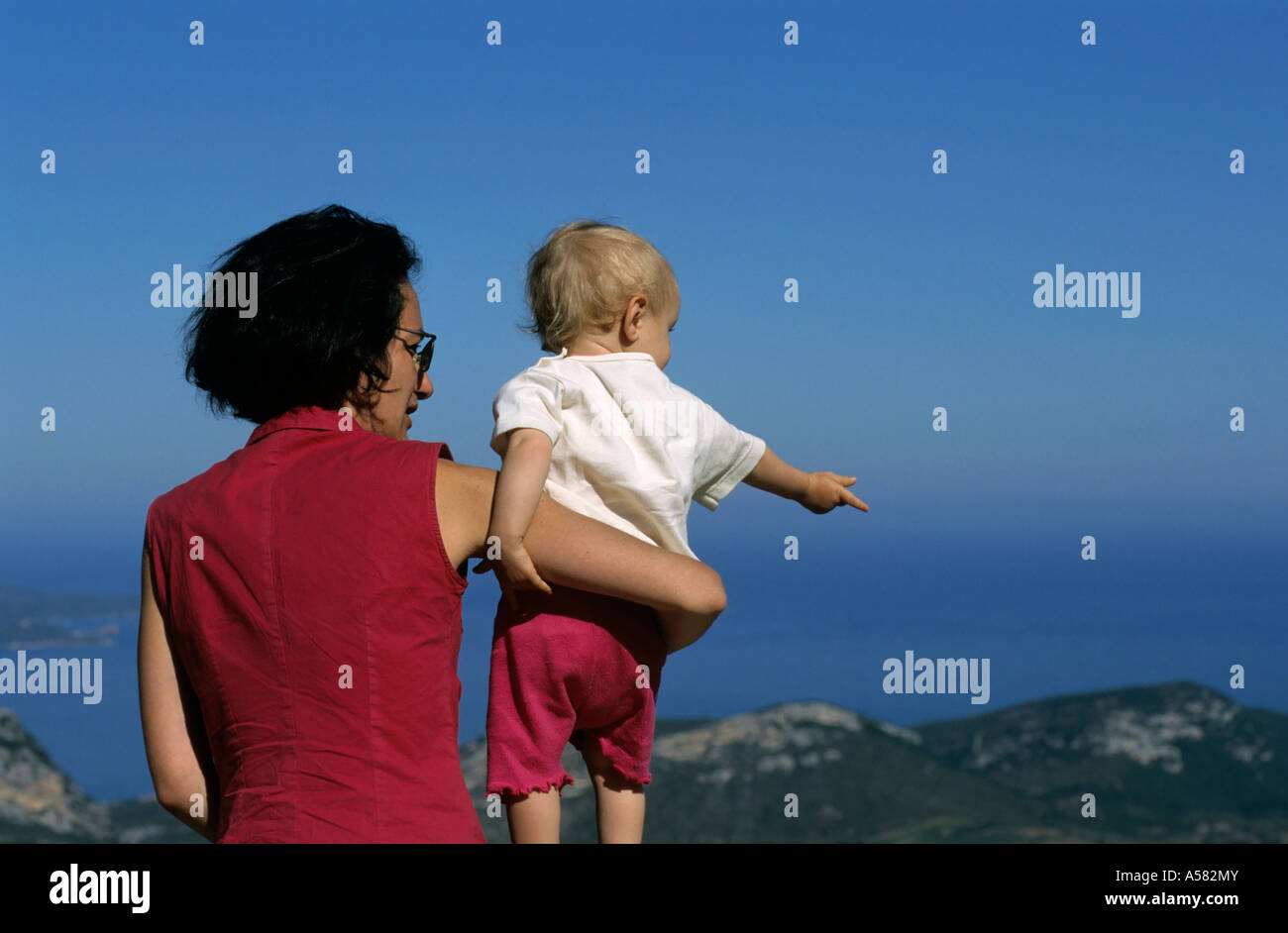 Madre tenendo la sua bambina mentre guardi una con vista sul mare Foto Stock