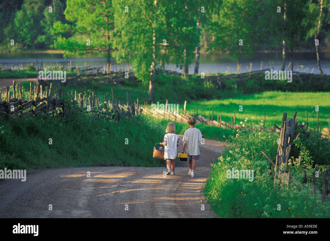 Due bambini andare sulla pesca picnic paese giù in strada Småland, Svezia Foto Stock