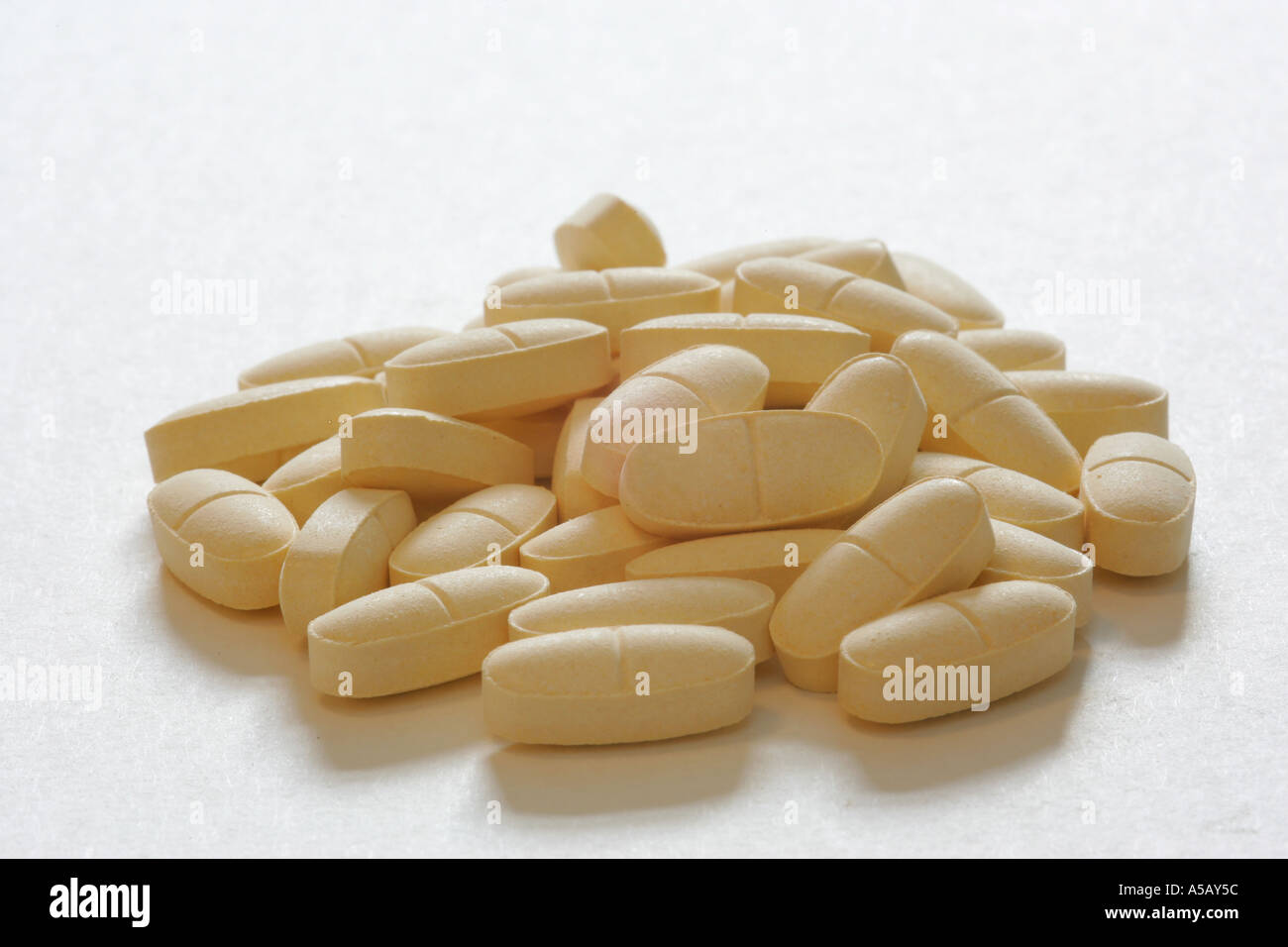 Pianura Generico crema gialla vitamina compresse pillole in una pila casuale su uno sfondo bianco medicina farmaci remedy supplemento gessose Foto Stock