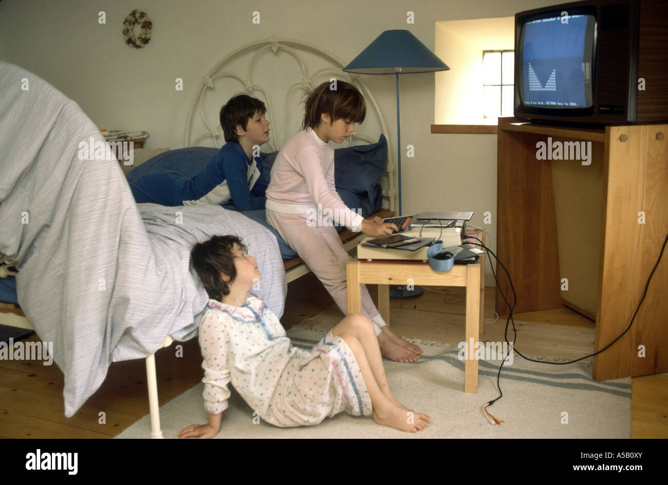 Primi computer games 1984 bambini che giocano al momento di andare a dormire Foto Stock