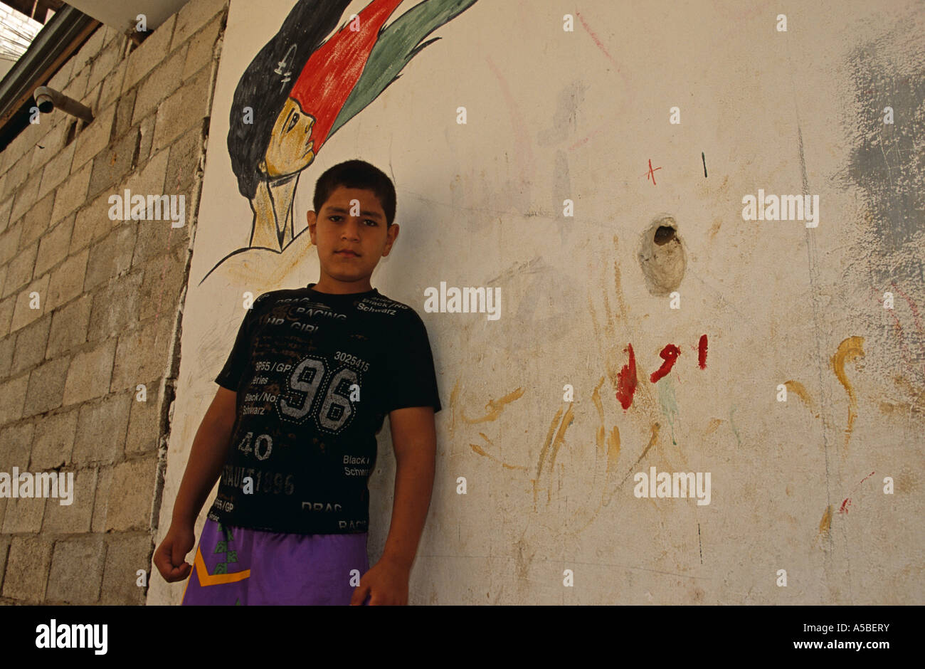 Un ragazzo in piedi contro un graffiti a Shatila campo profughi a Beirut Foto Stock