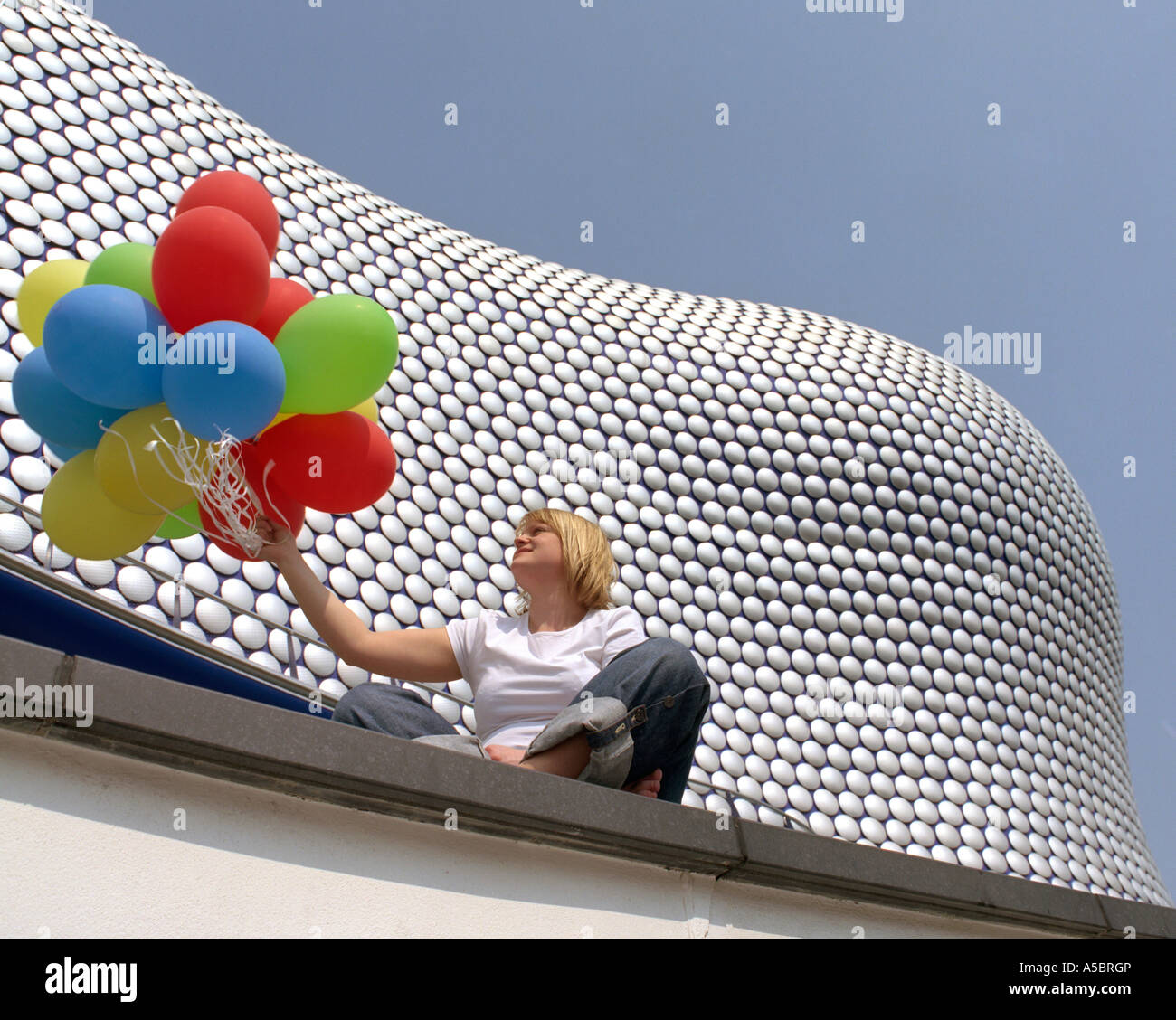 Donna sat holding palloncini. Selfridges Building, Birmingham, Regno Unito Foto Stock