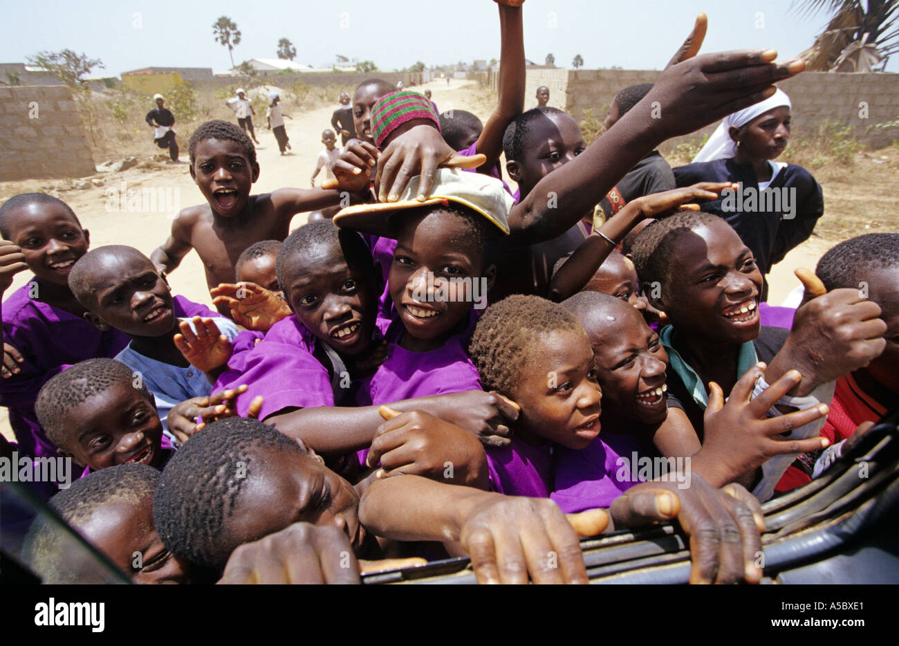 I bambini della scuola in Gambia affollarsi intorno minibus in eccitazione per salutare i turisti Africa occidentale Foto Stock