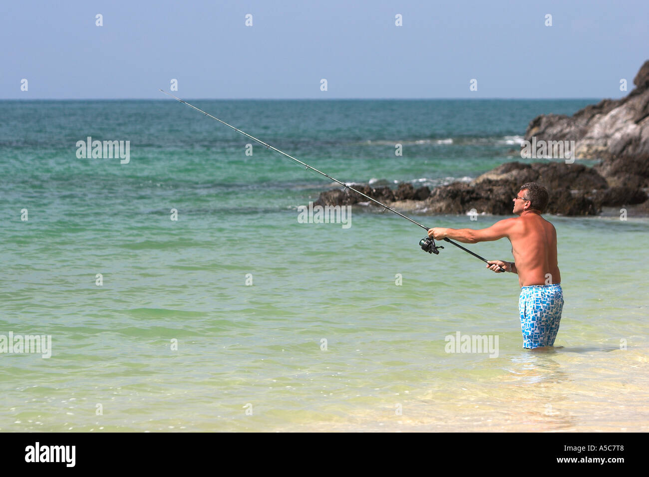 Uomo in pantaloncini surf pesca Phra Ae Long Beach Ko Lanta island Thailandia Foto Stock