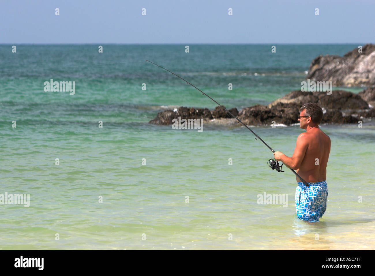 Uomo in pantaloncini surf pesca Phra Ae Long Beach Ko Lanta island Thailandia Foto Stock