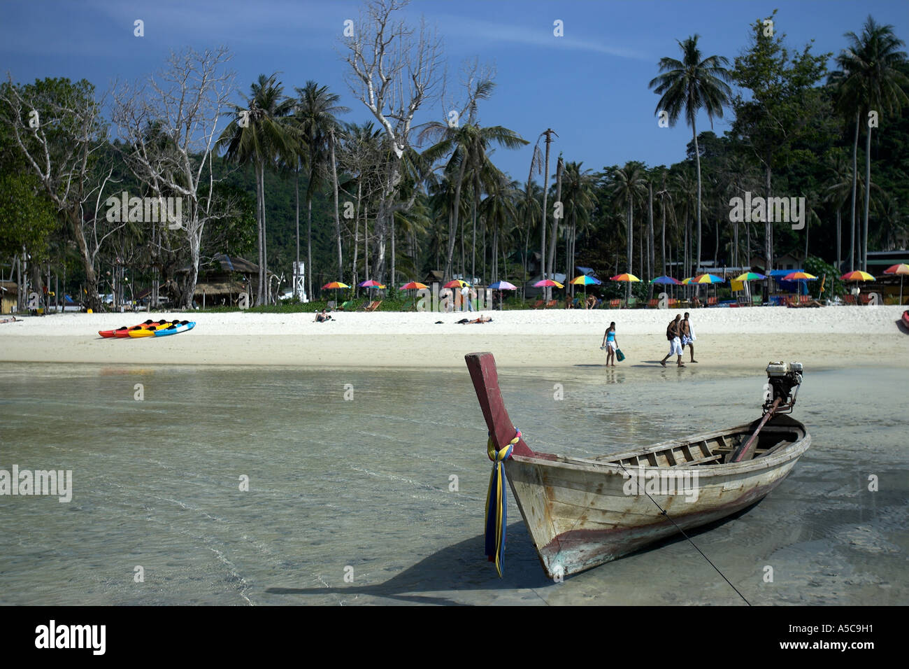 Longtail boat Ao La Dalam spiaggia fiancheggiato con ombrelloni colorati Phi Phi Island Thailandia Foto Stock