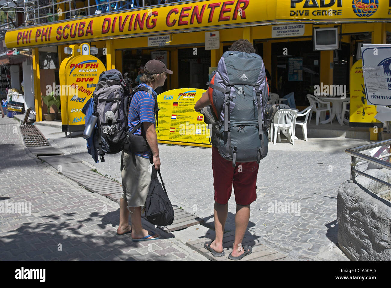 Backpackers guardare gli annunci di immersioni lungo il percorso dietro Ao Ton Sai beach Phi Phi Island Thailandia Foto Stock