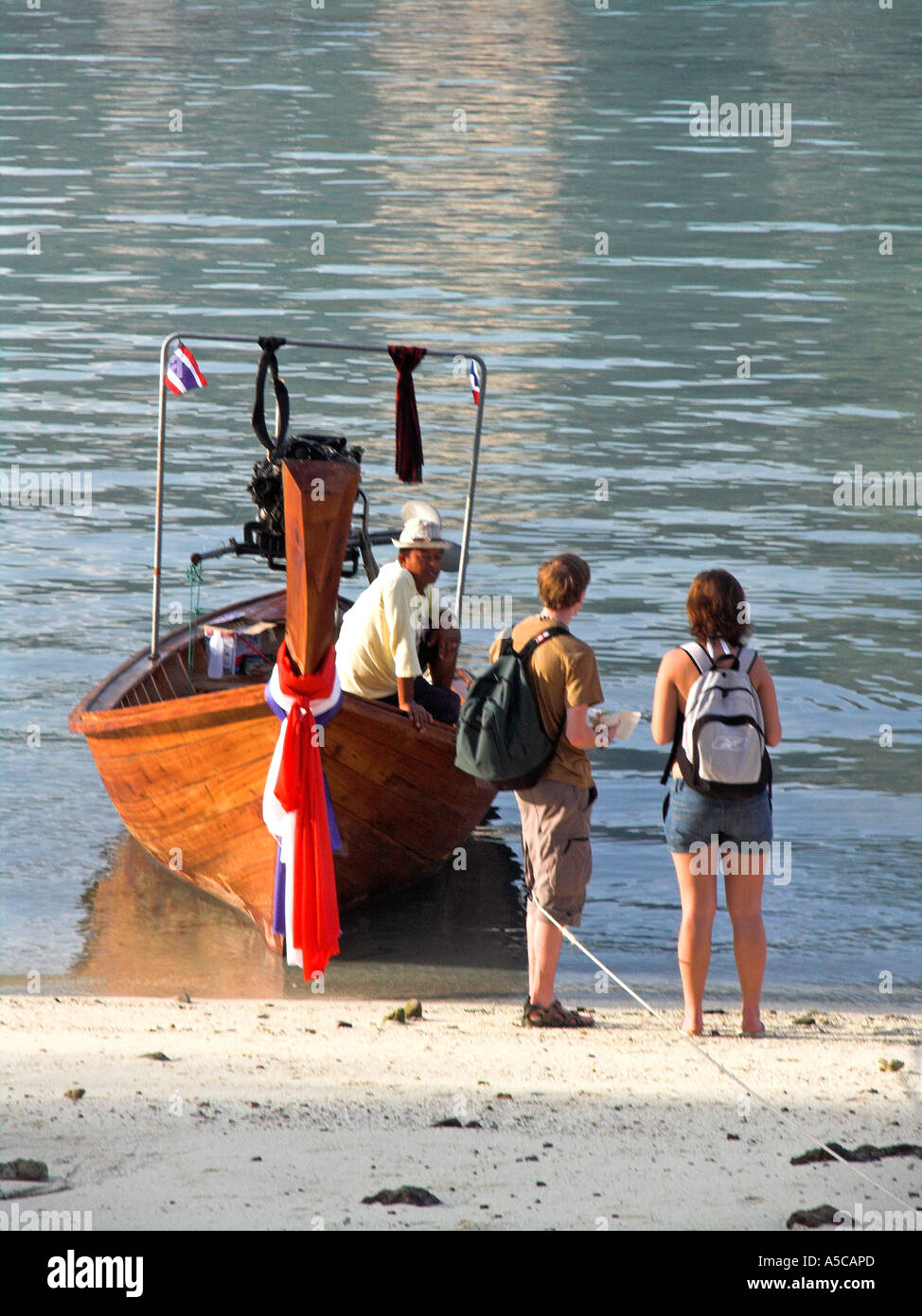 Coppia giovane negoziare con longtail barcaiolo per cavalcare Phi Phi Island Thailandia Foto Stock