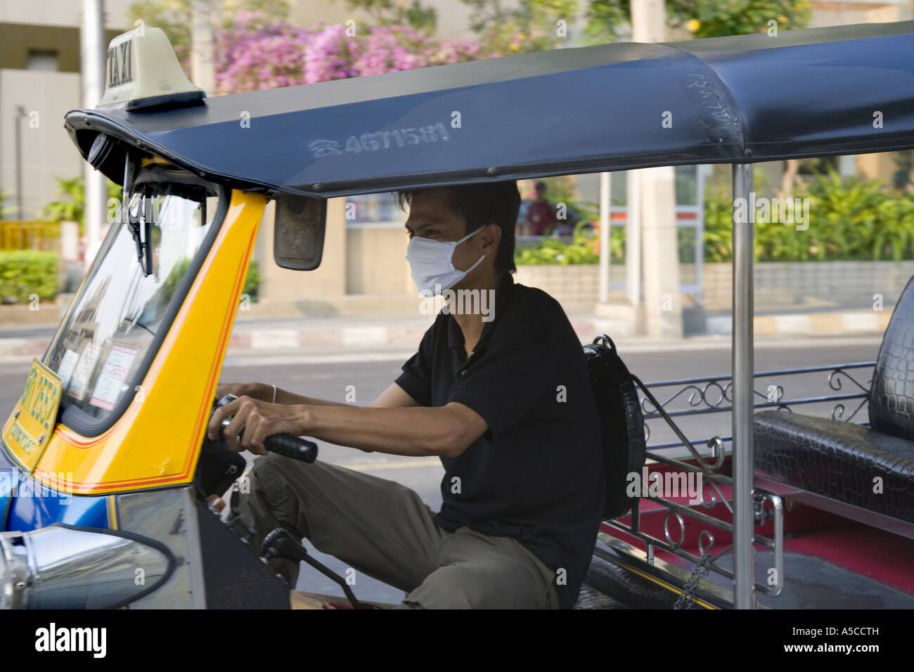 Protezione di smog nella trafficata capitale Bankok. Conducente di tuk-tuks taxi inquinamento da indossare maschera filtro veicolo di filtraggio dei fumi di scarico. Foto Stock