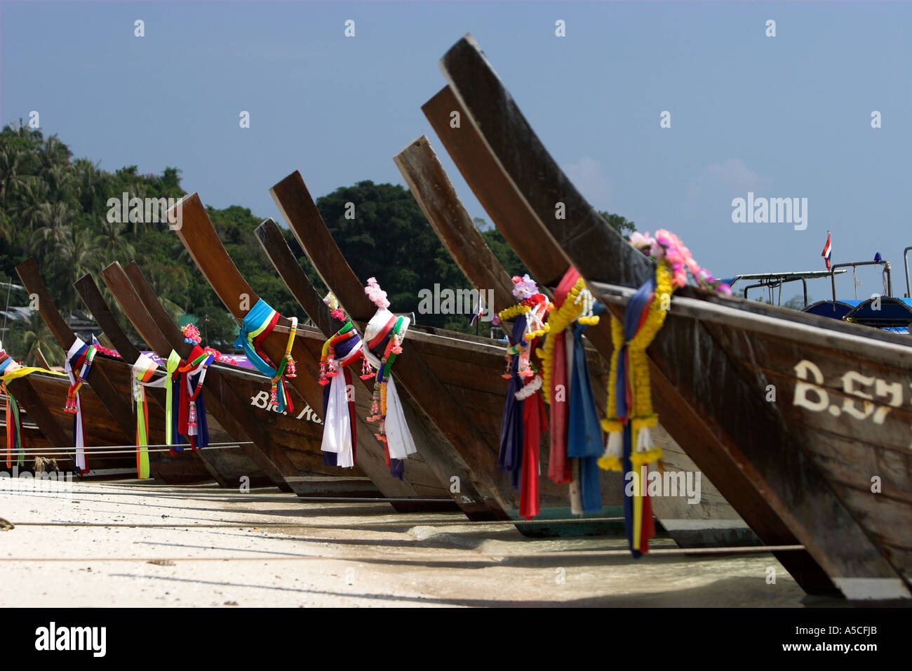 Longtail tradizionali barche con la preghiera buddista sciarpe tirata sulla spiaggia di Phi Phi Island Thailandia Foto Stock