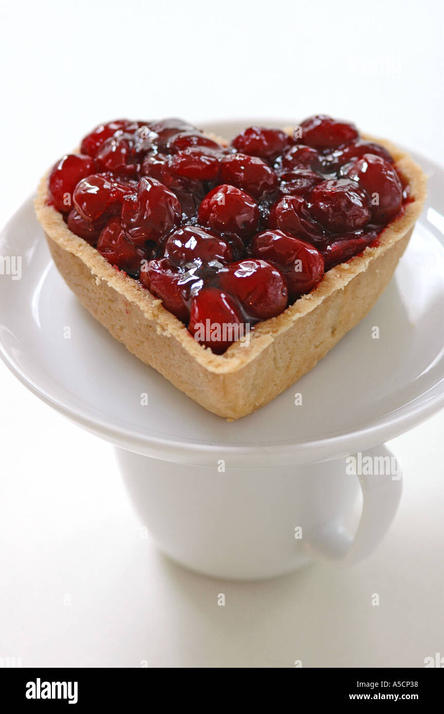 A forma di cuore crostata di ciliegia sul piattino bilanciamento sulla tazza Foto Stock