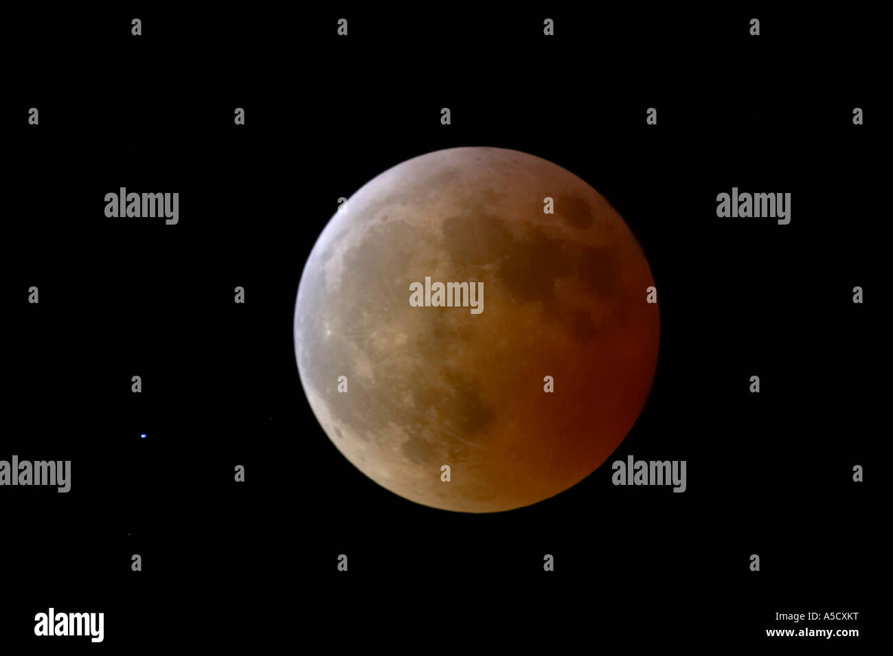 Luna diventa meno rosso come esce delle masse ombra subito dopo la totalità durante l'eclisse lunare totale in corso Foto Stock
