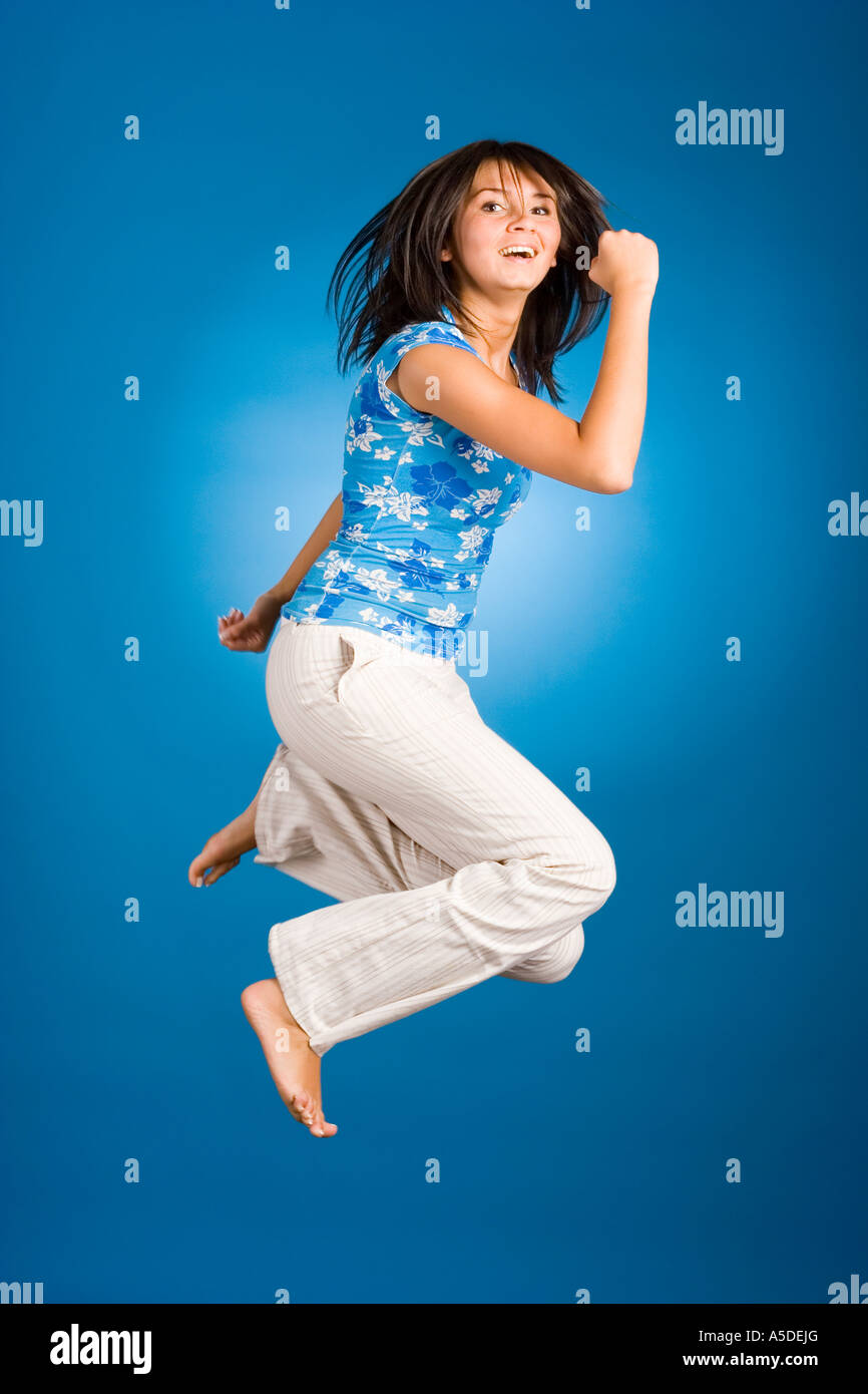 Jumping happy donna su sfondo blu Foto Stock