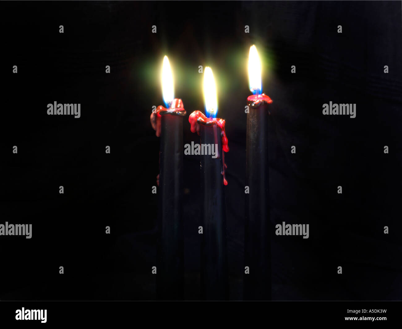 Tre candele nere con cera rossa gocciolamento verso il basso Foto Stock