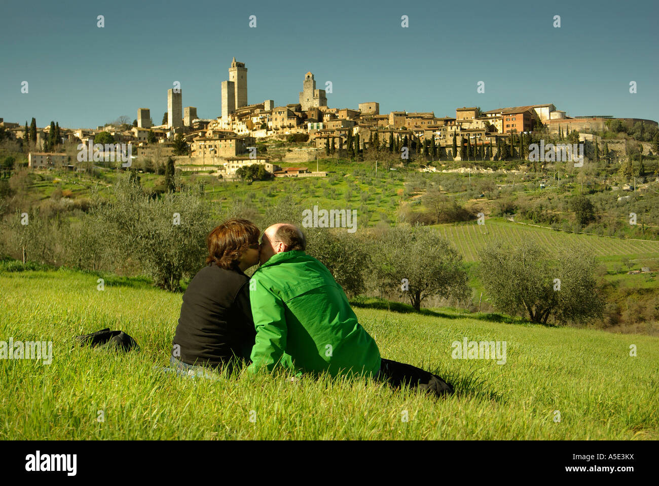 San Gimignano Toscana Italia giovane baciare sulla verde erba picnic contro il panorama delle tante torri in orizzontale Foto Stock
