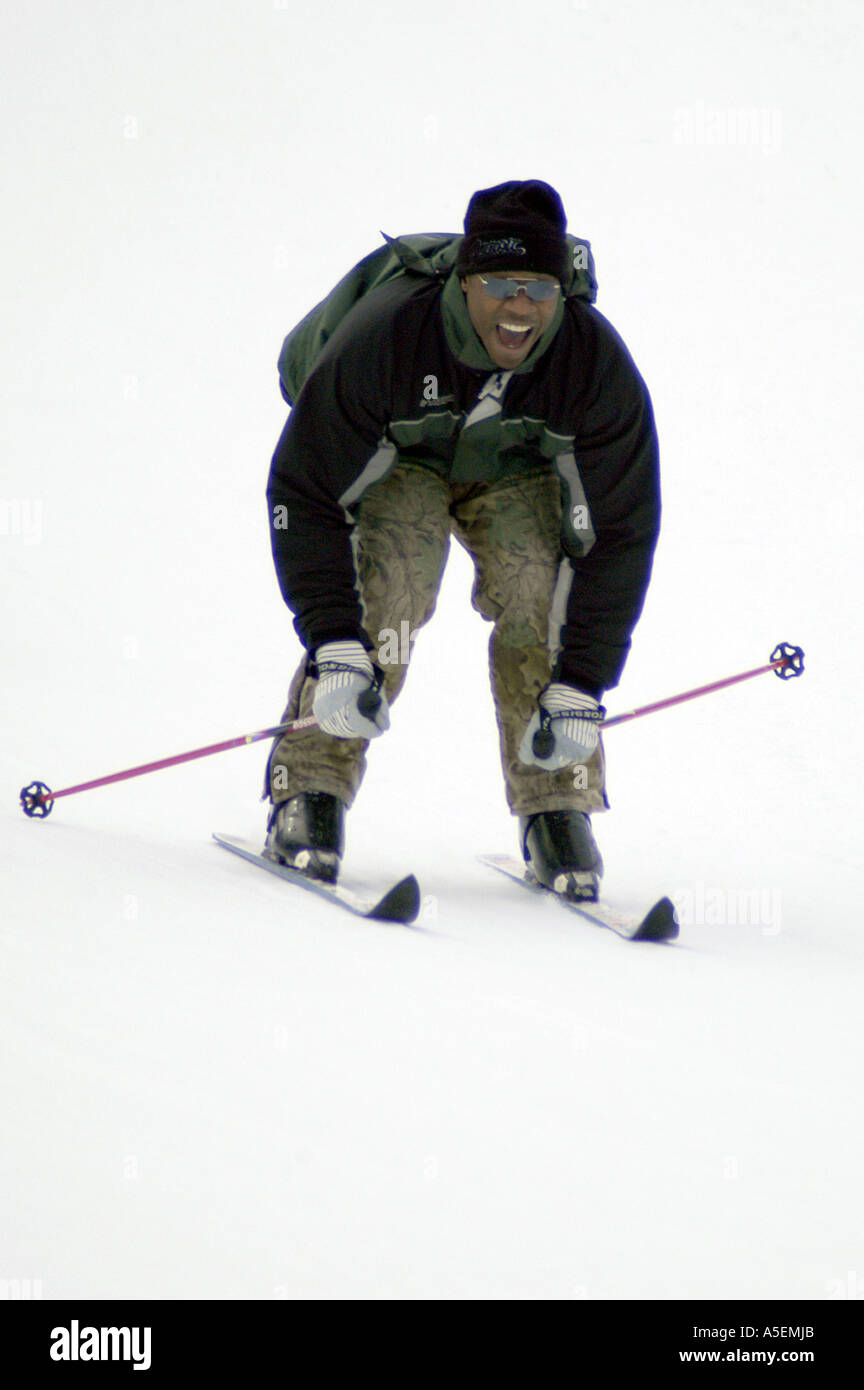 Uomo nero indossando occhiali sorrisi infilare in posizione durante il down-hill ski run Foto Stock