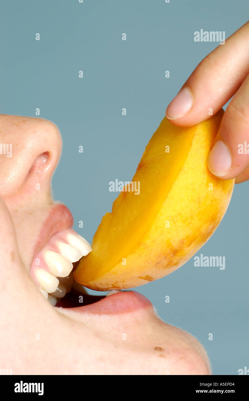 Che ricordano le pesche morde donna mordere in un pezzo di pesca Foto Stock