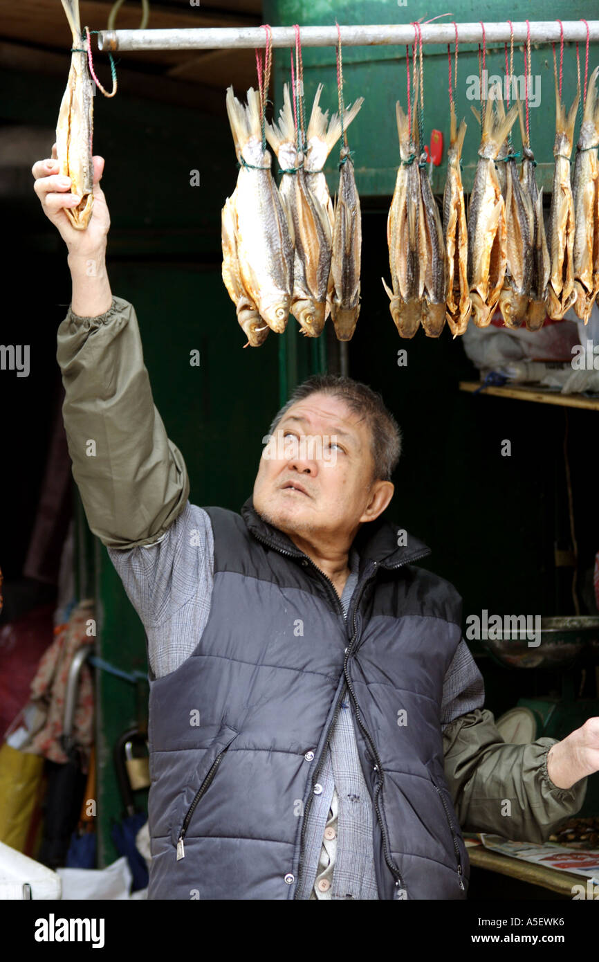 Di Hong Kong, Kowloon, mercato di Mongkok, fornitore appesi pesci secchi per la vendita Foto Stock