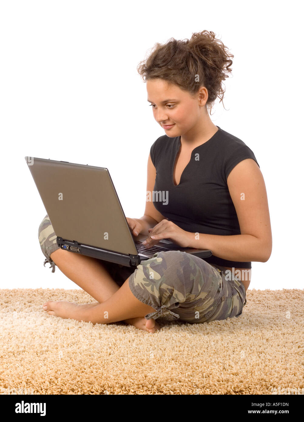 Isolato su bianco adolescente femmina seduta sul tappeto con il computer portatile Foto Stock