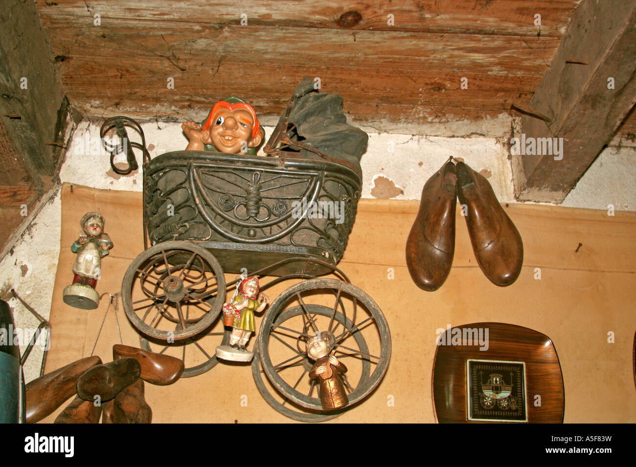 Un vecchio pram con un Quasimodo bambola in un negozio di antiquariato e forme per calzature appeso a una parete Foto Stock