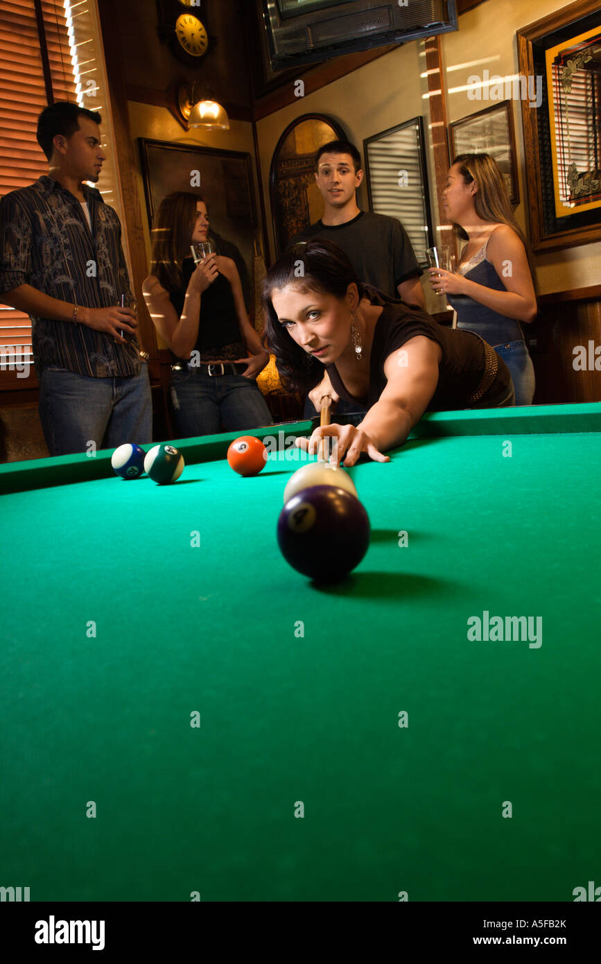 Giovane donna caucasica preparando per colpire la sfera in piscina mentre giocare biliardo Foto Stock