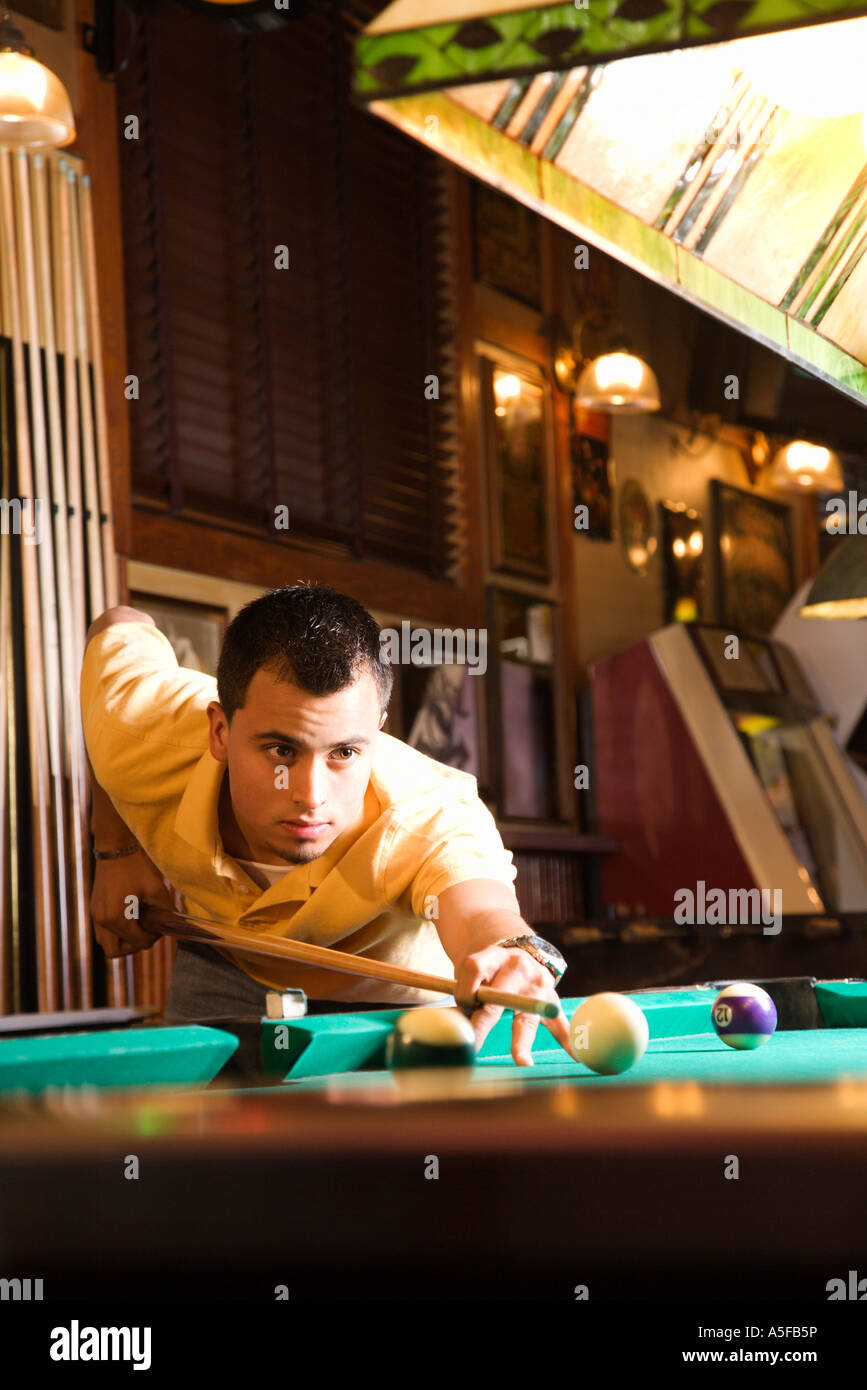 Giovane uomo concentrando mentre puntando alla sfera della piscina mentre giocare biliardo Foto Stock