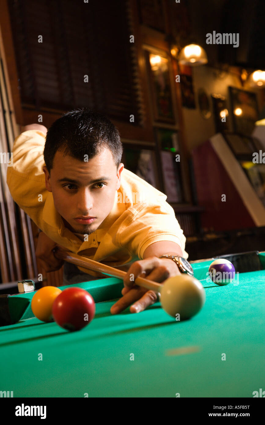 Giovane uomo concentrando mentre puntando alla sfera della piscina mentre giocare biliardo Foto Stock