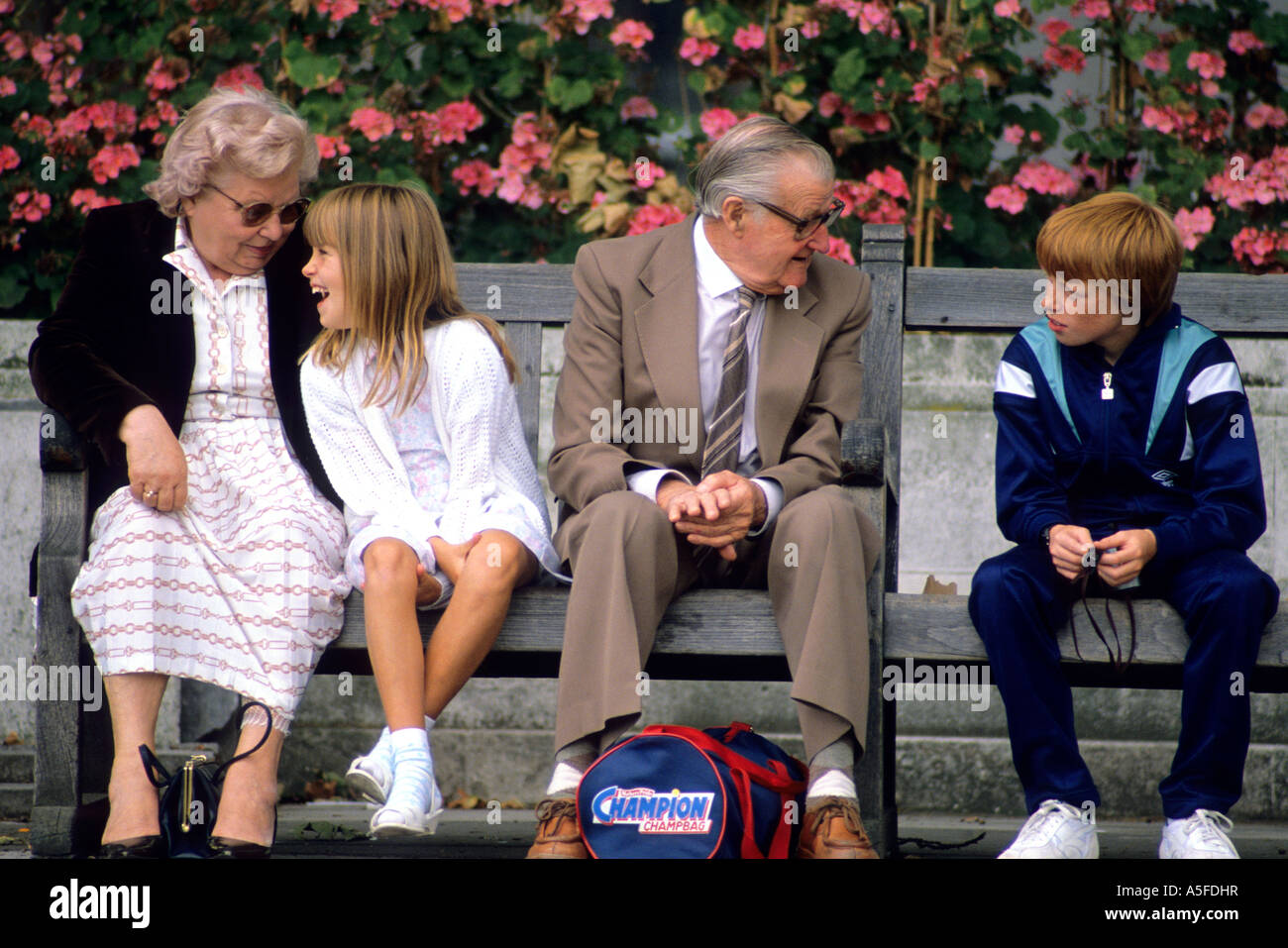 Visita i nonni con i loro nipoti su una panchina nel parco in London Inghilterra England Foto Stock