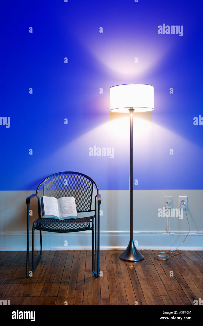 Blu luce di proiezione a parete con un luminoso lampada da terra e libro  aperto sulla sedia Foto stock - Alamy