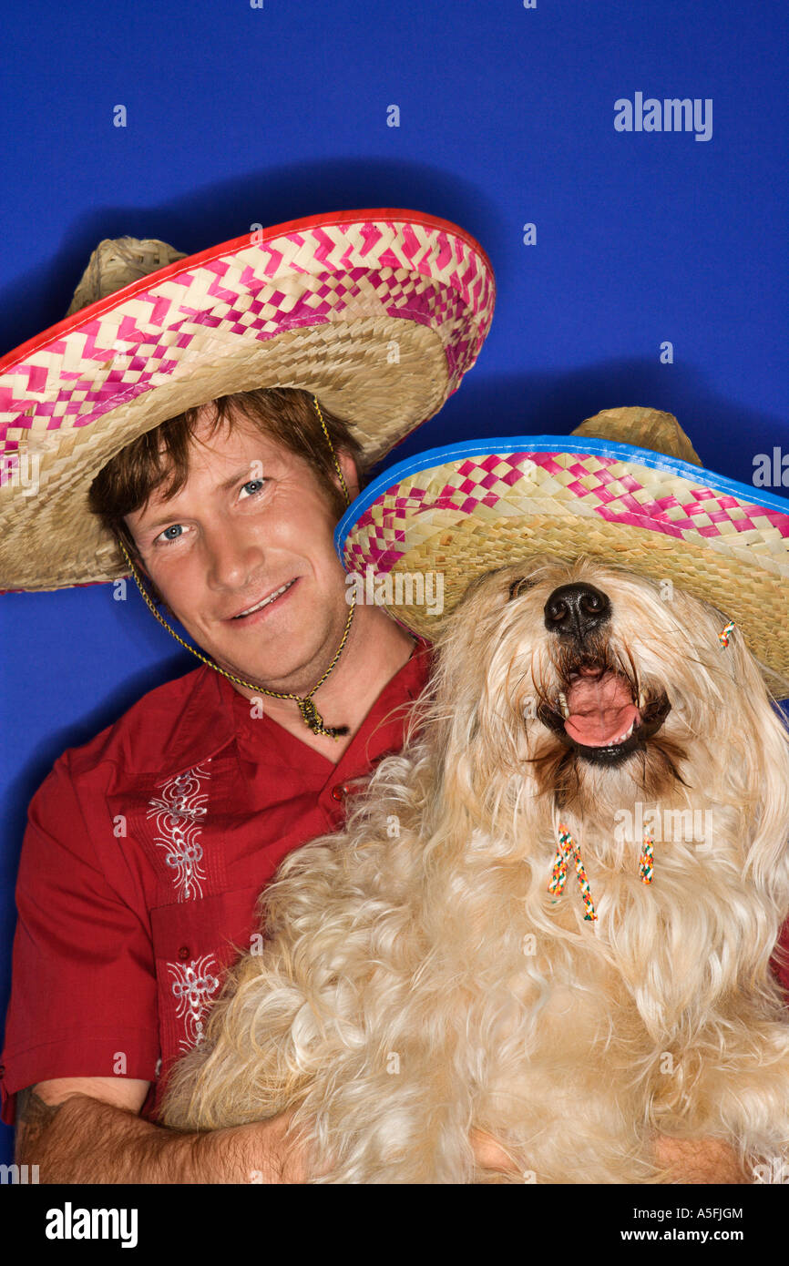 Soffici cane marrone e caucasici giovane maschio adulto indossando sombreros messicani Foto Stock
