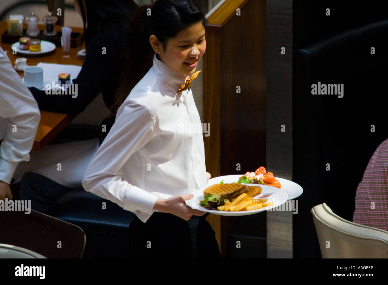 La cameriera che porta una piastra con un attraente Entree presso un ristorante di lusso Foto Stock