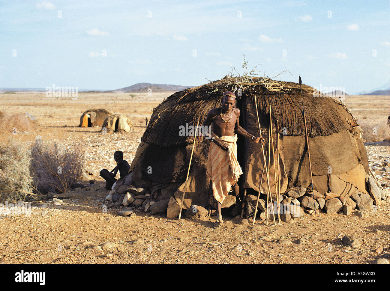 Rendille elder presso l'entrata alla sua capanna che è decorato con rami per celebrare il Nuovo Anno Kenya Africa orientale Foto Stock