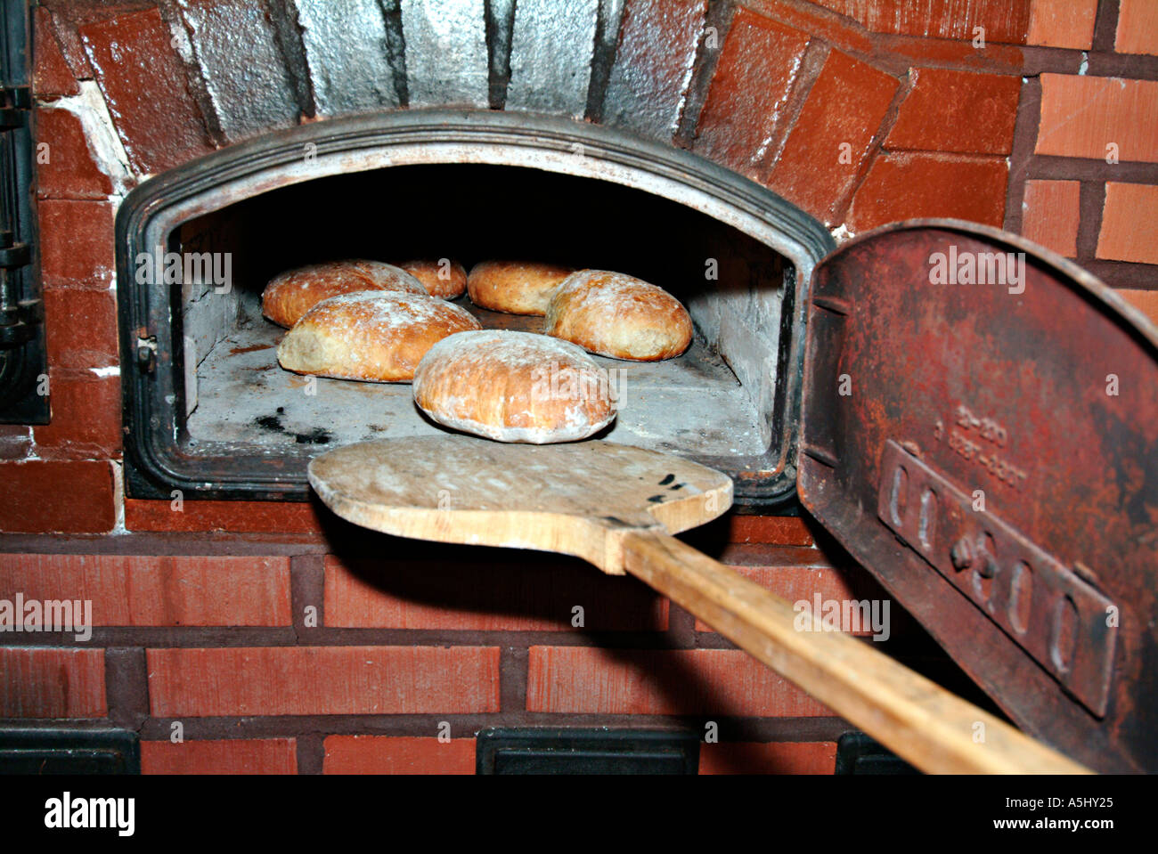 PR outloading pagnotte di pane al di fuori di un reso vecchio stufa di pietra Foto Stock