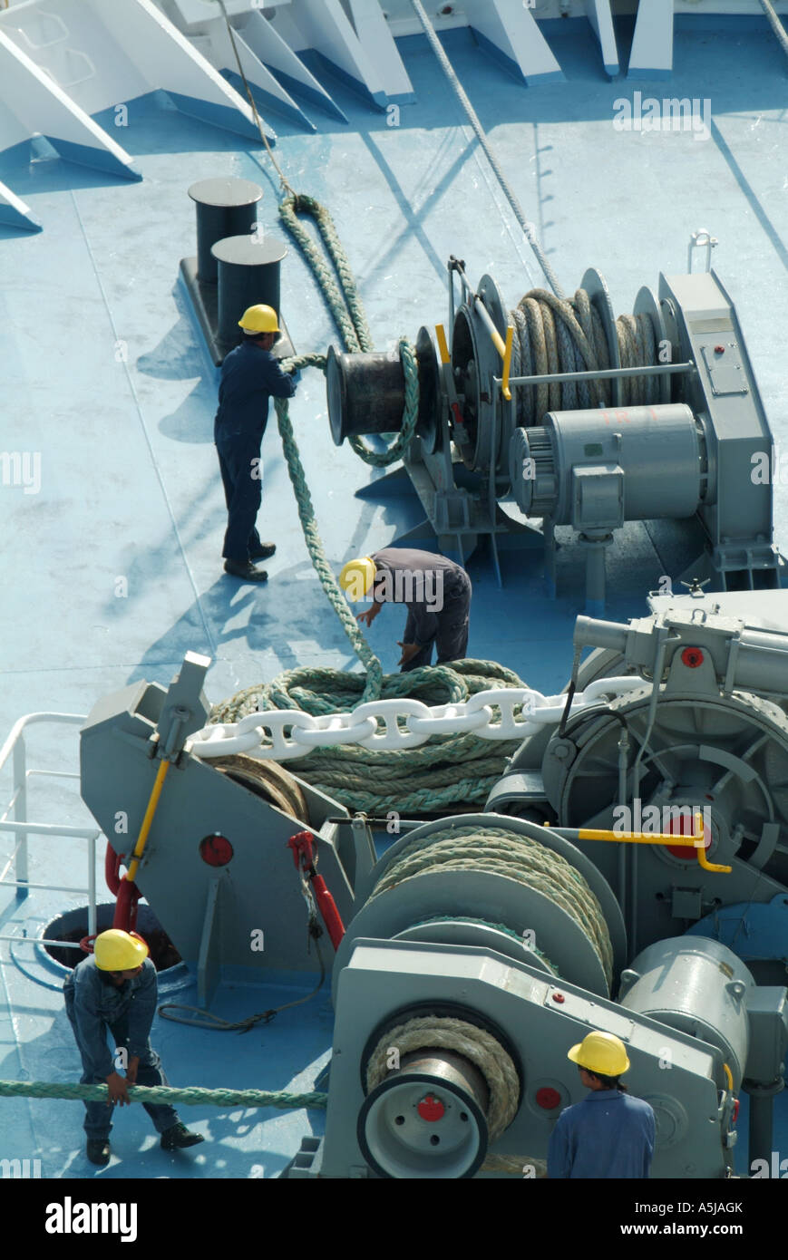 Guardando verso il basso a partire da sopra a prua della nave da crociera liner & navi uomini di equipaggio di lavoro funi di ormeggio sul avvolgimento meccanico marcia in partenza porto di Tarragona Spagna Foto Stock