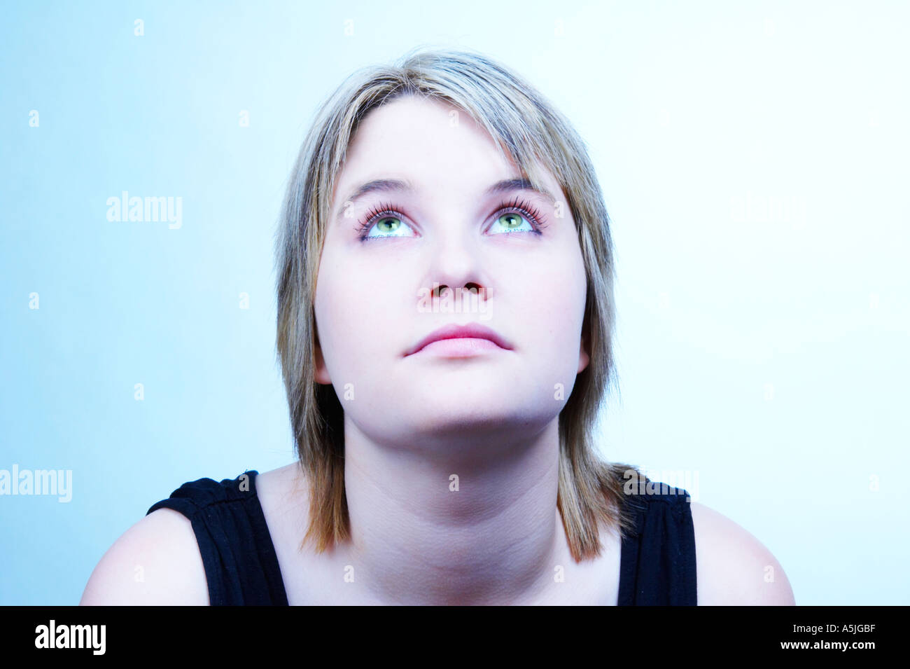 Ragazza adolescente guardando verso l'alto Bleeched orizzontale blu Foto Stock