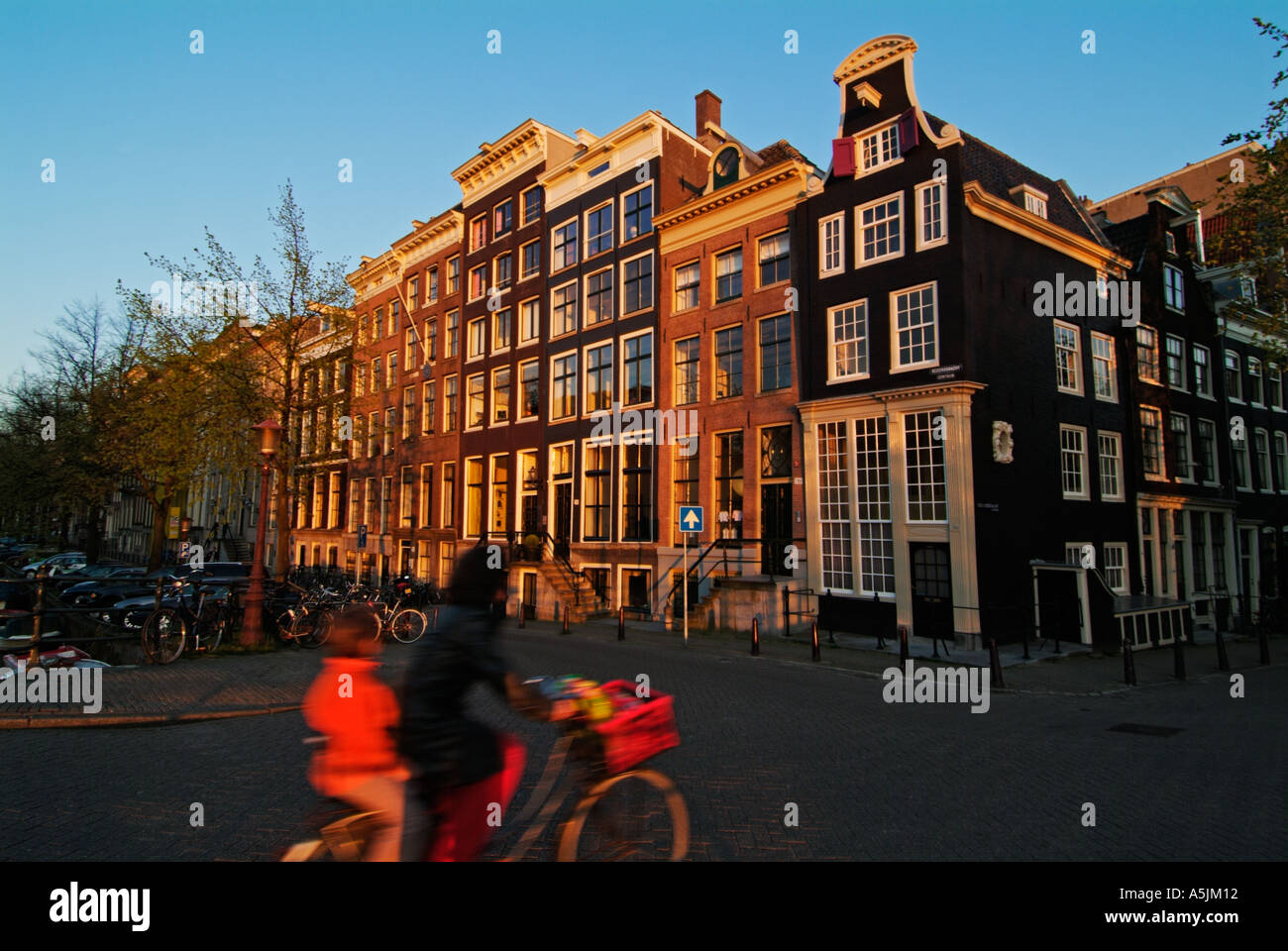 Ciclista con passeggero tornando a casa la sera su un ponte sul canale di Amsterdam Paesi Bassi Olanda UE Europa Foto Stock